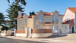 A multi-story residential building with a tiled roof, balconies, and a gated entrance. - Chalet Maria da Assunção - Studio (Cascais)