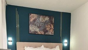 Una cama bien tendida con ropa de cama blanca y gris, un cabecero y un adorno decorativo en la pared superior.