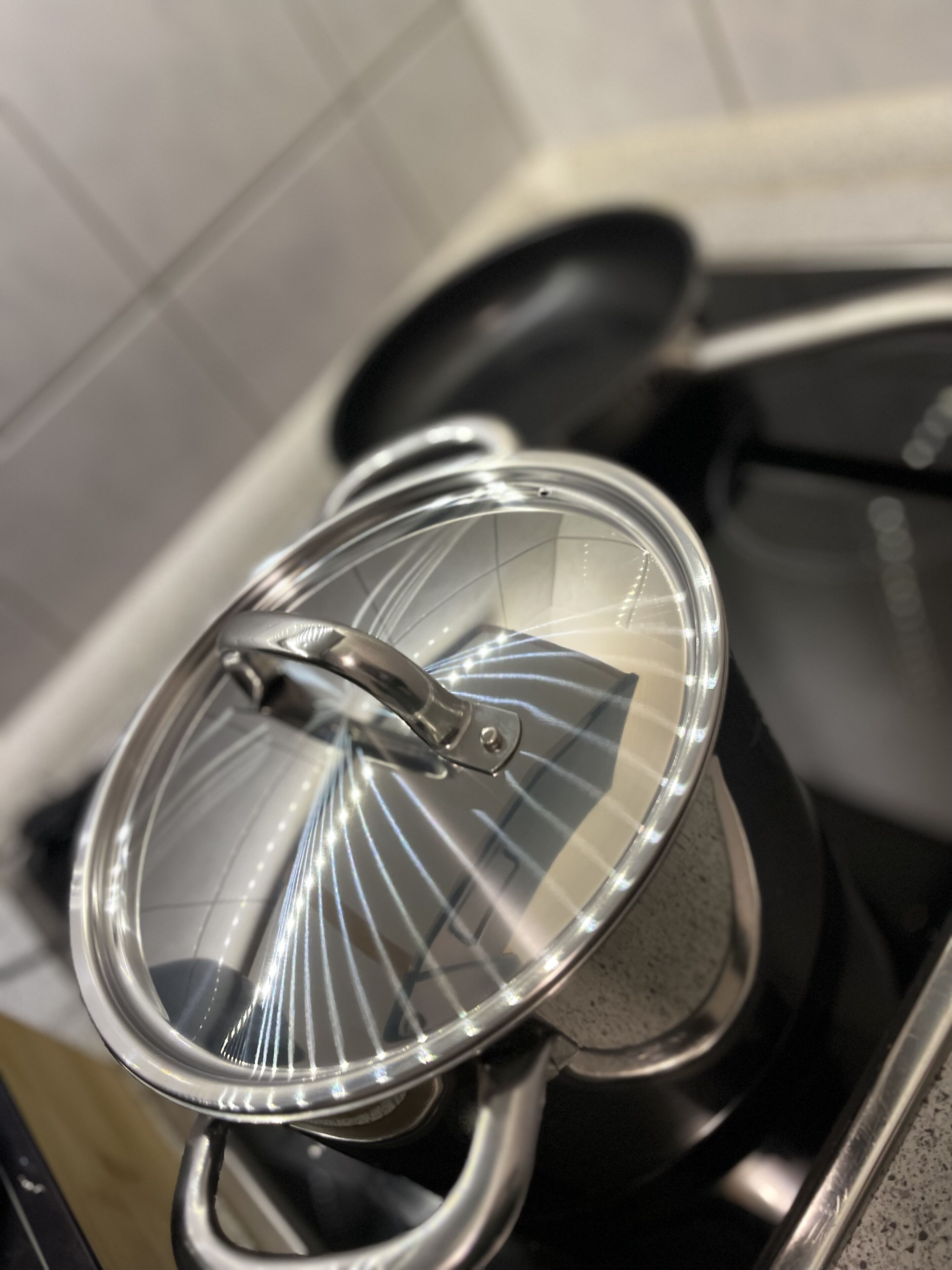 Una olla de acero inoxidable sobre una estufa con una tapa de vidrio.