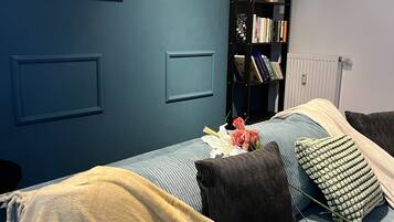 A bedroom with a bed, a bookshelf, a radiator, and a framed picture on the wall.