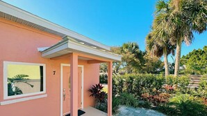 A pink building with a covered porch, a door, and a window.