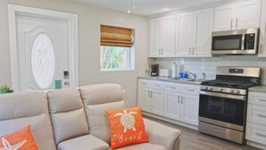 A modern kitchen with white cabinets, a stainless steel stove, and a microwave.