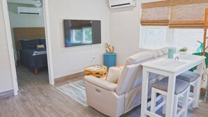 A modern living room with a sofa, a small table, and a TV mounted on the wall.