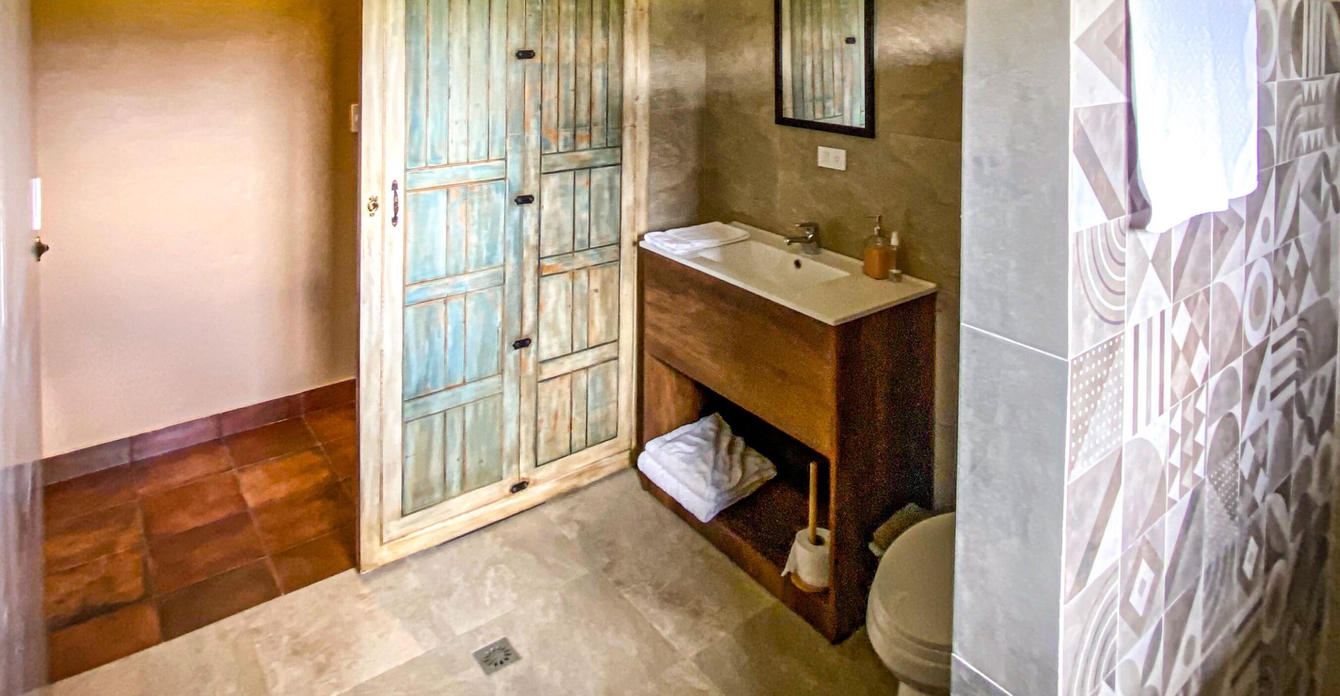 Un baño con puerta de madera, un lavabo y un inodoro.