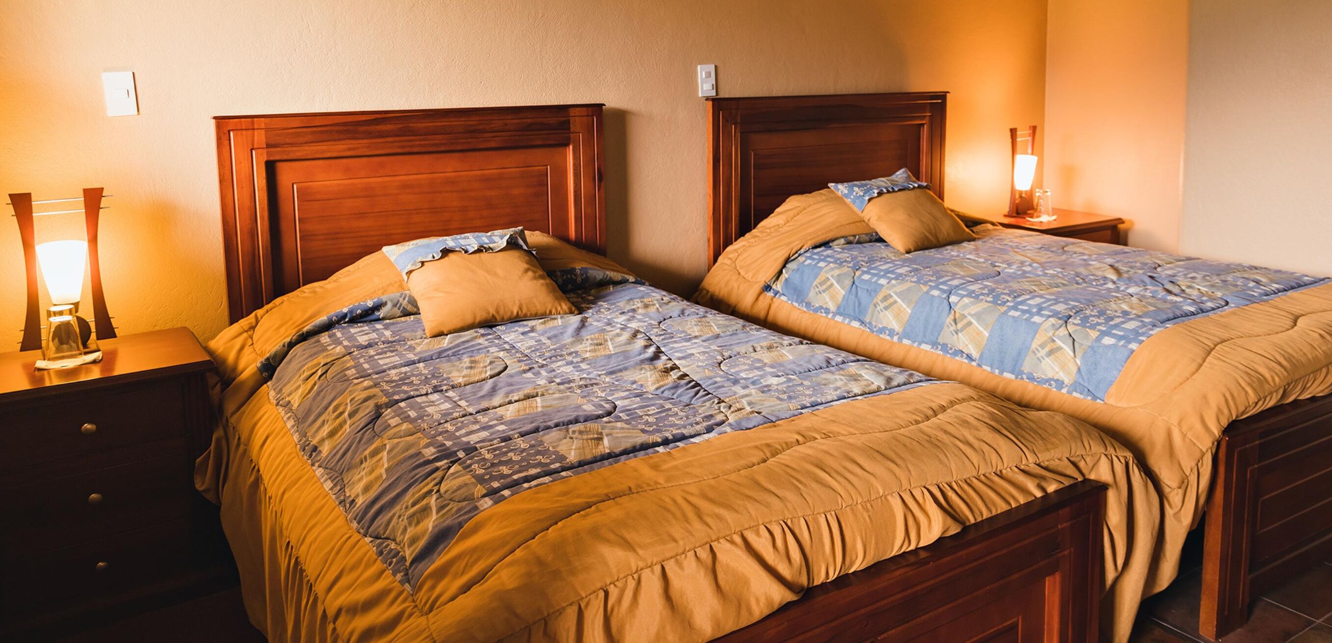Una cama doble con cabecera de madera y mesita de noche a juego.
