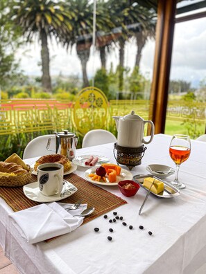 A breakfast table with coffee, pastries, fruit, and a glass of juice. - B&B Hostería Oro Azul (Cotacachi)