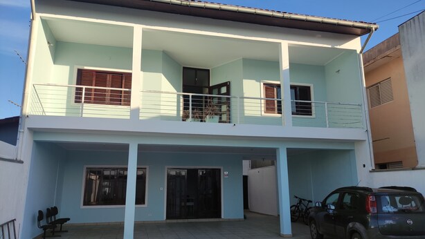 A two-story building with a balcony, large windows, and a car parked in front. - Casa do Bert Itanhaén (Itanhaém)