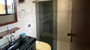 A bathroom with a sink, toilet, and glass-enclosed shower. - Casa do Bert Itanhaén (Itanhaém)