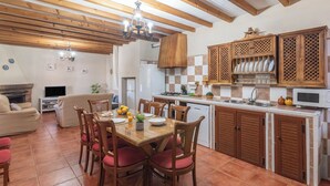 Un salon chaleureux avec une cheminée, une table à manger pour quatre personnes et une cuisine dotée de meubles en bois et d’un four à micro-ondes.