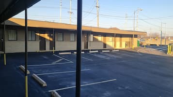 Un motel con estacionamiento, una zona techada y un edificio con varias habitaciones.
