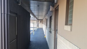 A corridor with a metal door on the left, a window on the right, and a door at the end. - DuBois Manor Motel  (DuBois)