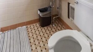 A bathroom with a white sink, a toilet, a mirror, and a window with curtains. - DuBois Manor Motel  (DuBois)