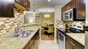 A modern kitchen with granite countertops, stainless steel appliances, and a dining area with a chandelier. - Luxe Condo 2 blocks from The Bellagio and Caesars Palace Jacuzzi, Pool & Fitness (Las Vegas)