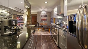 A modern kitchen with a coffee machine, stainless steel appliances, and a chandelier. - Luxe Condo 2 blocks from The Bellagio and Caesars Palace Jacuzzi, Pool & Fitness (Las Vegas)