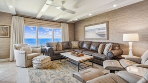 A modern living room with a sectional sofa, a coffee table, and a view of the ocean. - Spectacular Ocean Front Condo on the Omni Plantation (Fernandina Beach)