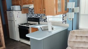 A compact kitchen with wooden cabinets, a white refrigerator, a stove, and a small island counter.