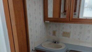 A bathroom with a wooden cabinet, a sink, and a toilet.