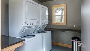 A laundry area with stacked washers and dryers, a window, and a trash can. - Scenic, Full-Hookup Back-In Campsite Just Outside Nashville! (Mt. Juliet)