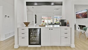 A modern kitchen with white cabinetry, a dishwasher, and a large window. - Luxury Villa: Pool, Spa, Golf Views  Sleeps 12 (Indio)