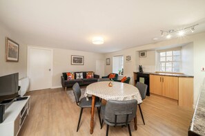 A dining area with a round table, chairs, and a kitchen in the background. - Unique Castle Stay in Perth - Corporate & Couples (Perth)