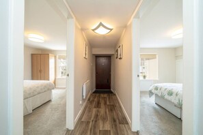 A narrow hallway with a wooden floor, flanked by two bedrooms with beds and a wardrobe. - Unique Castle Stay in Perth - Corporate & Couples (Perth)