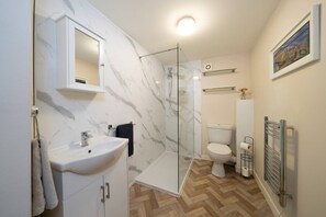A modern bathroom with a marble sink, glass shower enclosure, toilet, and a radiator. - Unique Castle Stay in Perth - Corporate & Couples (Perth)