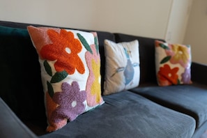 A dark-colored sofa with three decorative pillows featuring floral patterns. - Unique Castle Stay in Perth - Corporate & Couples (Perth)