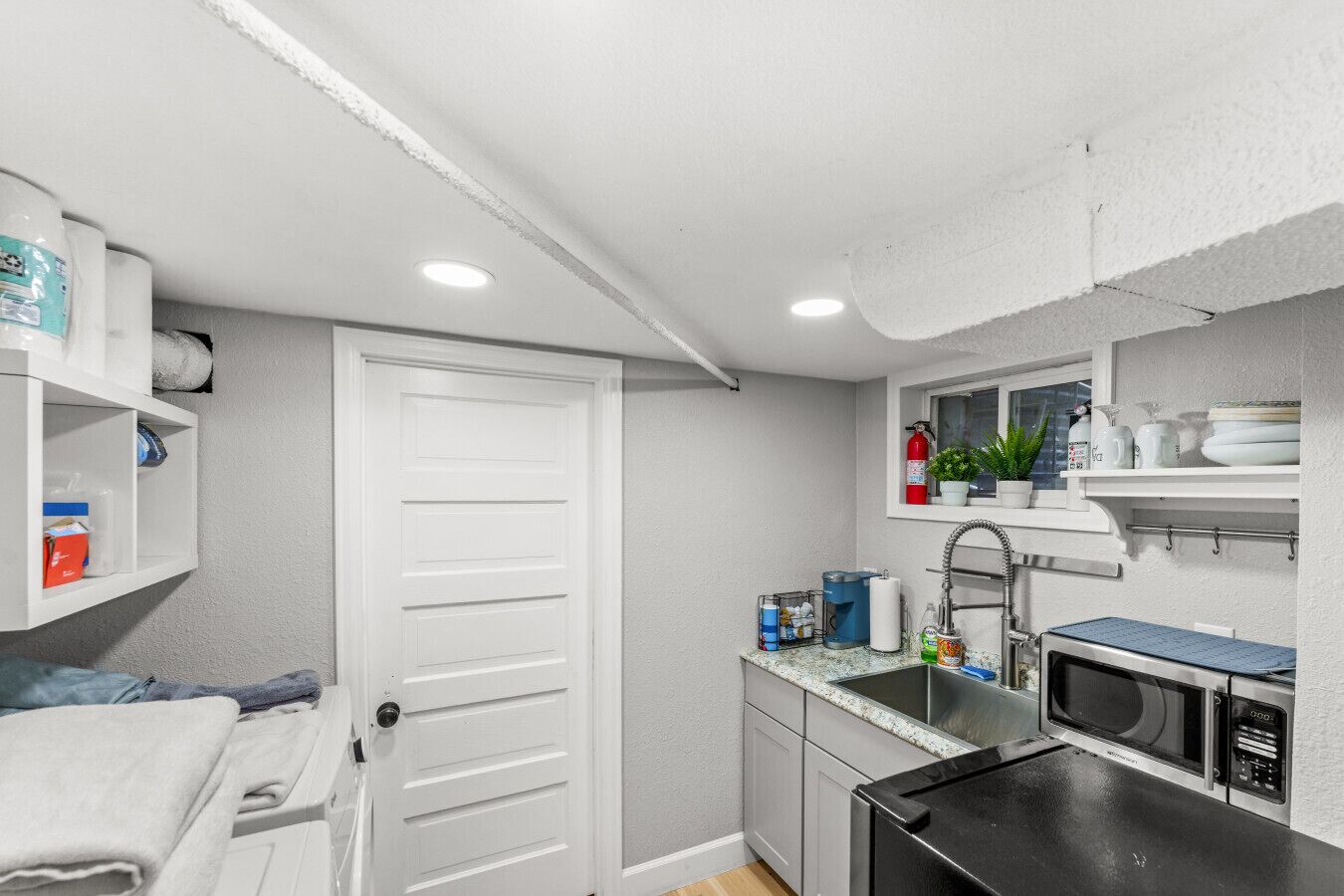 A compact kitchen with a microwave, sink, and storage shelves.