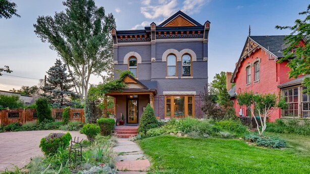 A two-story house with a front porch, a well-maintained garden, and a red and gray exterior. - Artsy Victorian I Near RINO I Downtown (Denver)