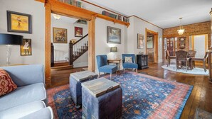 A spacious living room with a wooden staircase, a dining area, and a library. - Artsy Victorian I Near RINO I Downtown (Denver)