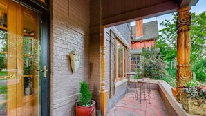 A covered outdoor area with a brick wall, a wooden door, a potted plant, and a metal table. - Artsy Victorian I Near RINO I Downtown (Denver)