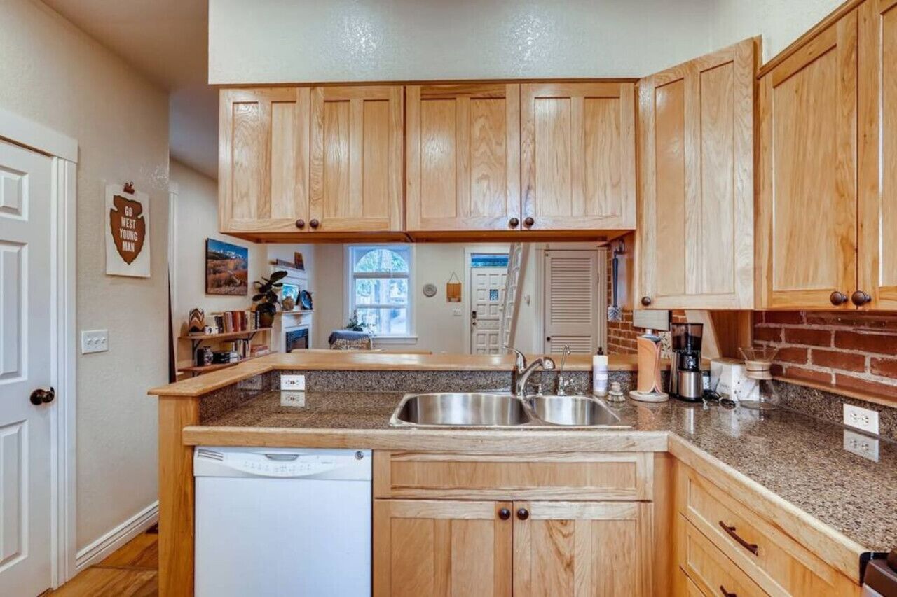 A kitchen with wooden cabinets, granite countertops, a dishwasher, and a window.