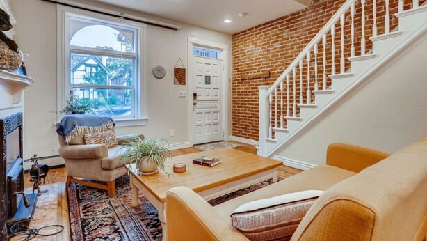 Un salon avec un mur en briques, un escalier et une grande fenêtre.
