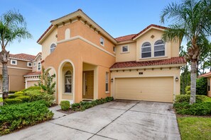 A two-story house with a beige facade, a red-tiled roof, and a garage.