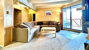 A cozy living room with a sectional sofa, a coffee table, and a large sliding glass door leading to a balcony. - Fireplace I Pool I Biking I Skiing & Snowboarding (Silverthorne)