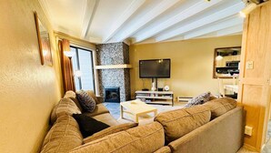 A living room with a sectional sofa, a coffee table, a flat-screen TV, and a fireplace. - Fireplace I Pool I Biking I Skiing & Snowboarding (Silverthorne)