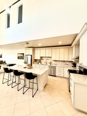 A modern kitchen with a central island, bar stools, and a dining area. - Luxury Loft I Skyline Views in RiNO (Denver)