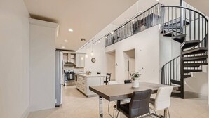 A modern kitchen with a dining area, a staircase, and a view of the living room. - Luxury Loft I Skyline Views in RiNO (Denver)