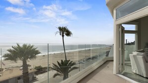 Ein Balkon mit Blick auf den Strand, Palmen und einen klaren Himmel.