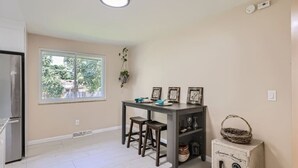 A kitchen with a dining table, chairs, a refrigerator, a window with a view, and a security safe. - Pet Friendly I 3bd I Red Rocks I Belmar I Denver (Lakewood)