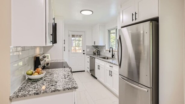 A modern kitchen with white cabinets, a stainless steel refrigerator, and a granite countertop. - Pet Friendly I 3bd I Red Rocks I Belmar I Denver (Lakewood)