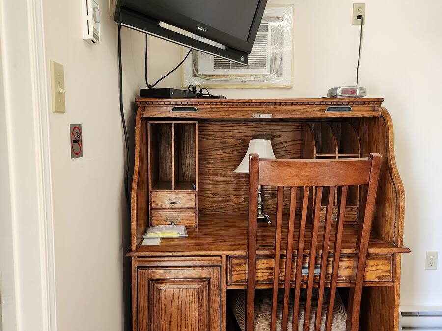 Un escritorio de madera con una televisión, una lámpara y una silla.