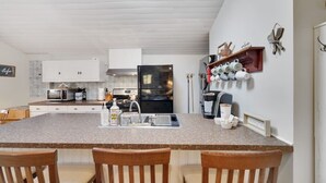 A kitchen with a granite countertop, white cabinets, a refrigerator, a coffee machine, and a coffee station. - Family Friendly Cabin I Firepit+Hot Tub I Poconos (Pocono Pines)