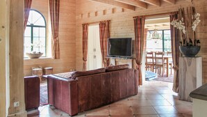 Ein gemütliches Wohnzimmer mit einer braunen Ledersofa, einem Flachbildfernseher und einem Essbereich mit Holztisch und -stühlen.