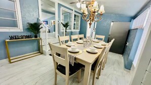 A dining area with a table set for six, a chandelier, and a 'WELCOME' sign on a console table.