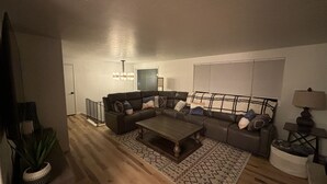 Ein Wohnzimmer mit Ecksofa, Couchtisch, Teppich mit Muster und einer Lampe.