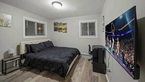 A bedroom with a bed, a TV, and a window with blinds. - Modern 2BD Apartment Near Royal Oak (Hazel Park)
