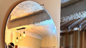 Ein kleiner Raum mit Küchenzeile, einem Bett und einem großen Spiegel, der das Interieur widergibt.
