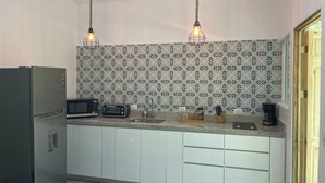 Een moderne keuken met witte kastjes, een ingebouwde magnetron, een broodrooster en een koffiezetapparaat.