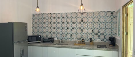 A modern kitchen with white cabinets, a built-in microwave, a toaster, and a coffee maker.